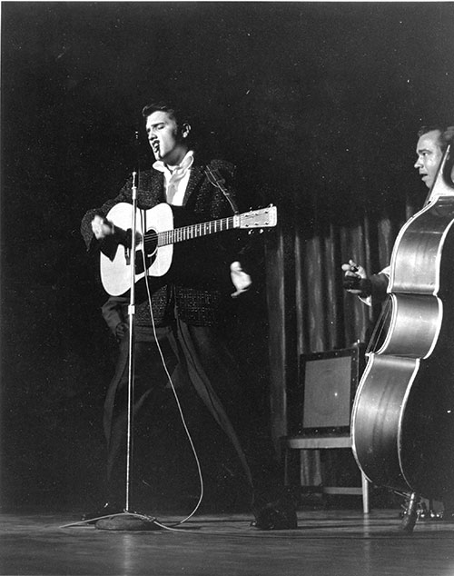 Historic photo of Elvis singing and playing guitar