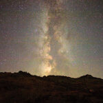 The Milky Way visible in a starry sky with a mountain silhouetted in front