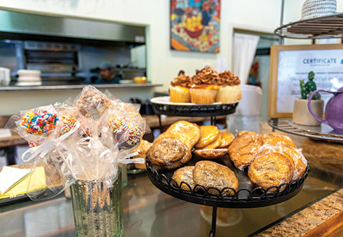 Countertop with baked goods: cupcakes, cake pops, and cookies