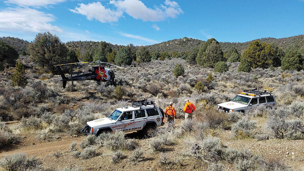 Search and Rescue members with vehicles and helicopter in the high desert.