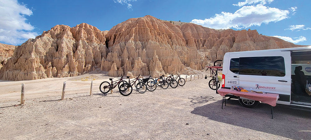 Many mountain bikes and a van, parked in front of the slot canyons at Cathedral Gorge State Park
