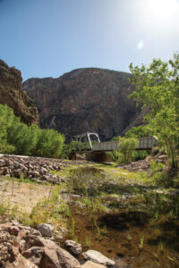 River running through rainbow canyon with a bridge in the distance.