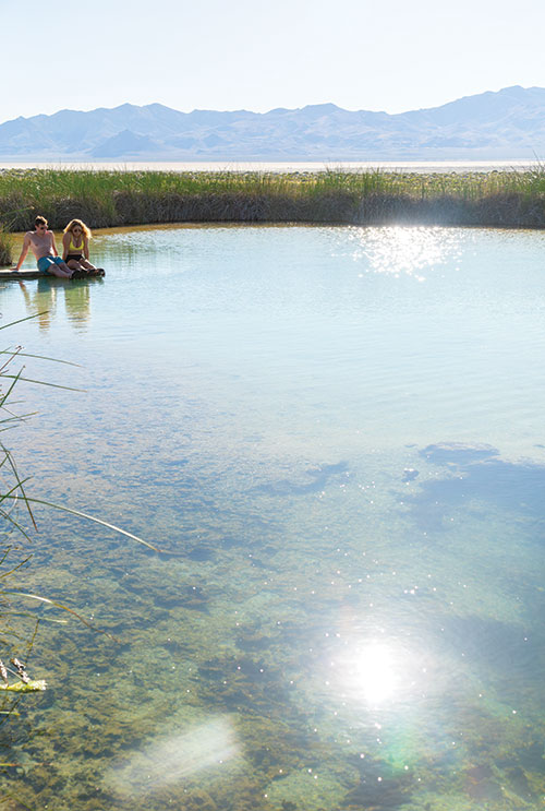 A couple sits with their feet in the water at Black Rock Hot Springs