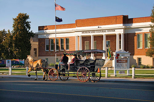 A horse-drawn carriage with people inside, in front of the Carson Valley Museum & Cultural Center. Photo ©Jay Aldrich