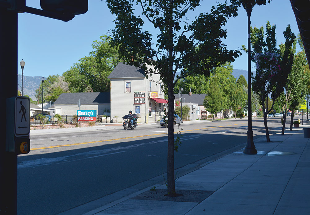 Main street of Gardnerville, showing motorcycle riders, Battle Born Wine shop, and the sign for Sharkey's Casino.