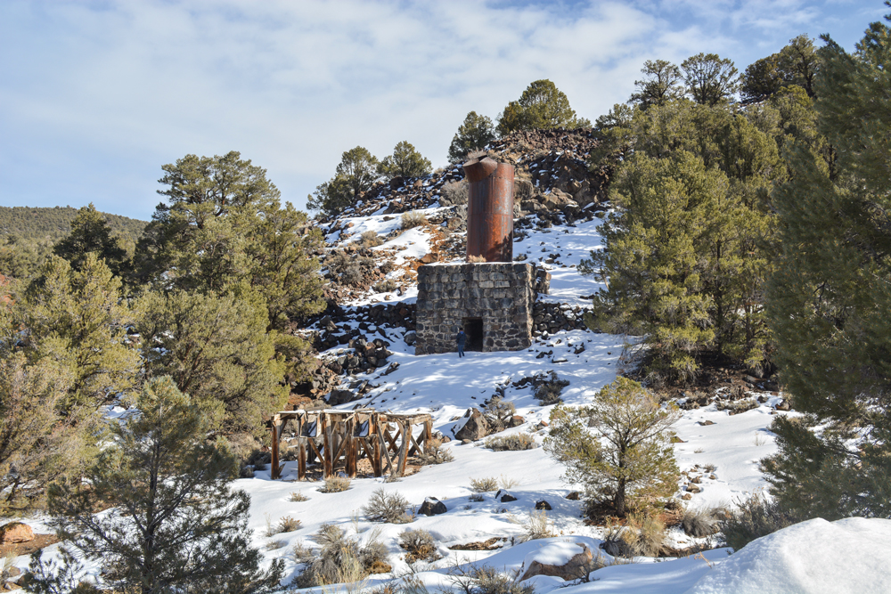 Man standing in front of old mining furnace at Aurora ghost town.