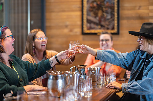 A group of women laugh and toast with locally-sourced spirits at Minden Mill Distilling.