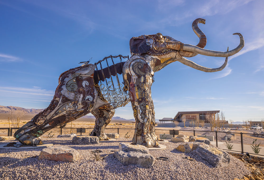 A large steampunk-style elephant sculpture, with the Ice Age Fossils State Park Visitor Center in the background.