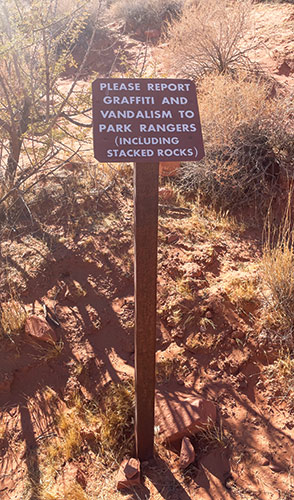 A sign that reads "Please report graffiti and vandalism to park rangers (including stacked rocks)"