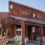 The front of an old wooden building, with a skull hanging on it. Jiggs Bar