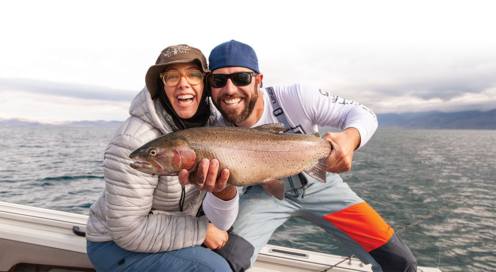 A couple on a boat in Pyramid Lake hold up a large fish for the camera