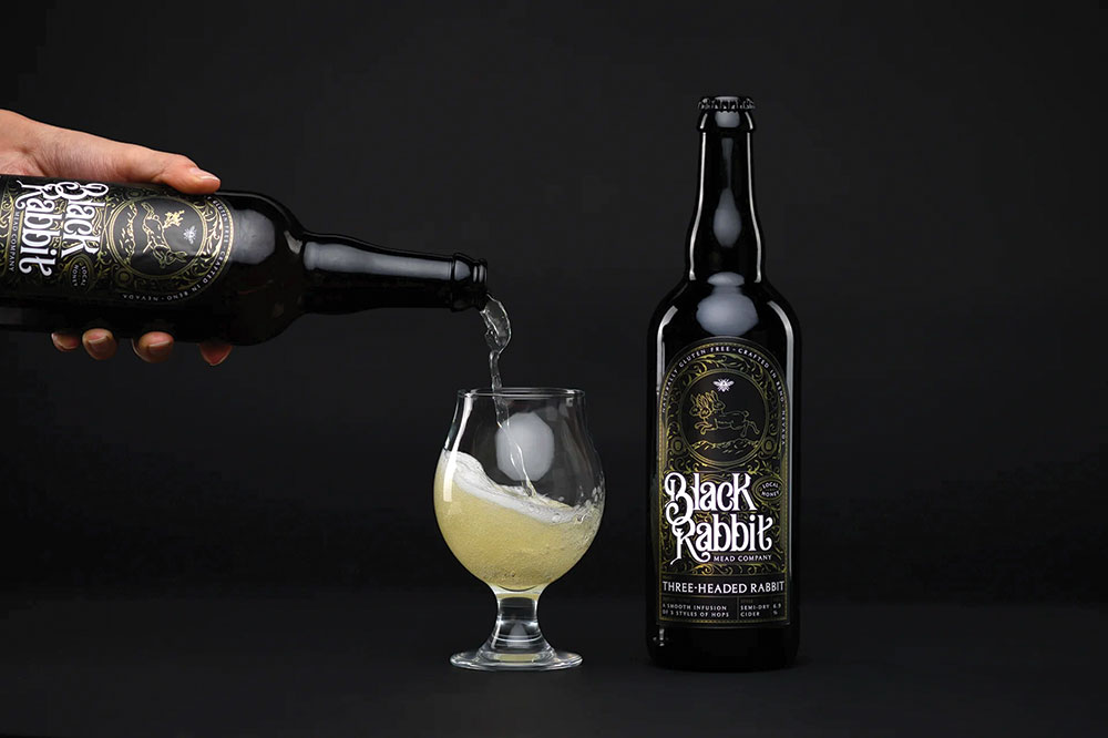 Black Rabbit Mead Company in Reno, a person's hand is pouring some mead into a glass. Another bottle sits nearby.