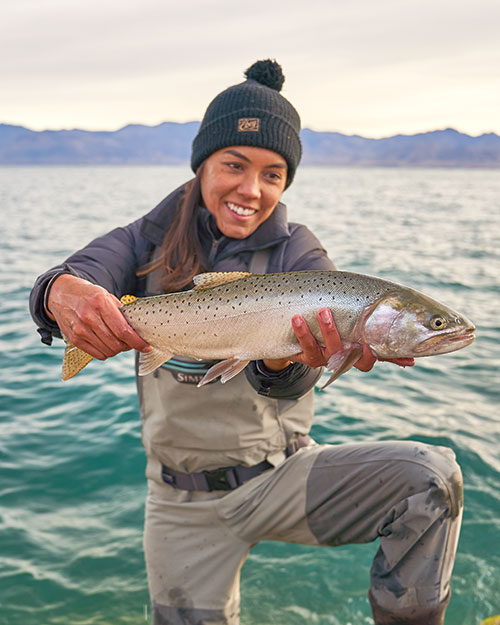 A woman holds a large fish up for the camera