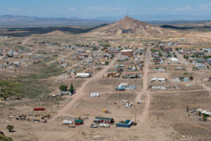 A photo of Goldfield in 2023. This image is in contrast to the 1906 overview picture of Goldfield, having being shot by the same perspective. In this photo, you can see the amount of buildings the own possessed has dwindled significantly, with most streets still remaining dirt while the main street has been paved. The large mountain can still be seen towering over the town, but now possesses a large 'G' on it as well as a large radio tower. 