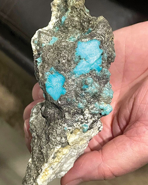 A large piece of turquoise in a person's hand.